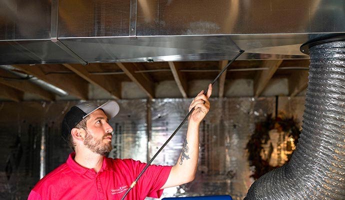 A professional cleaning an air duct vent
