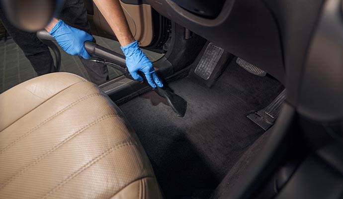 A person using a vacuum cleaner cleaning inside of a car
