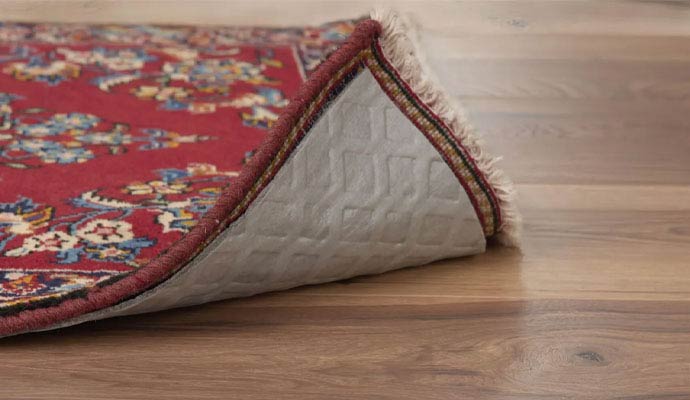 A close-up view of a thick non-slip padding underneath a decorative area rug