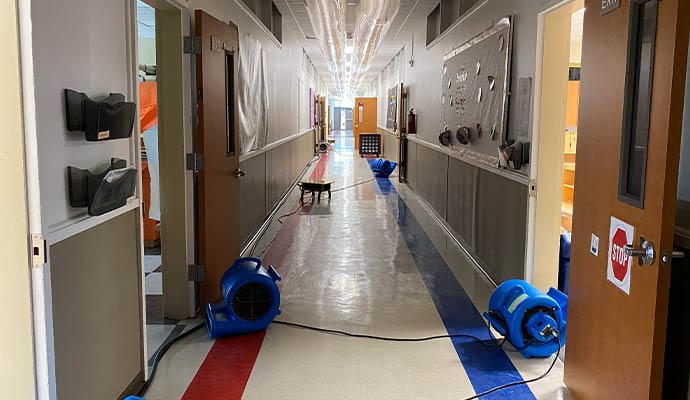 Water damage restoration service in school hallway